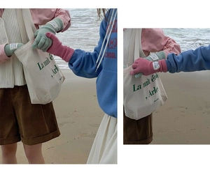 Detailed close-up of wool knit long gloves in vibrant colors on a person at the beach