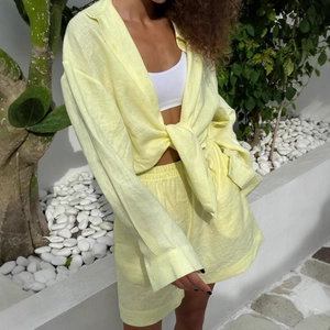 Detail of yellow two-piece linen set showing knotted long sleeve shirt and matching shorts