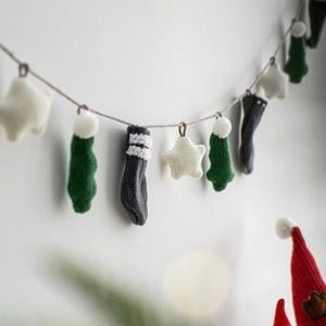 Knitted Christmas bunting flag decoration with green, grey and white stars on wall