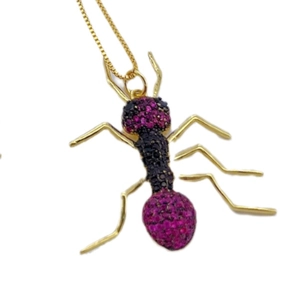 Gold ant pendant necklace with red and black zircon crystals on white background