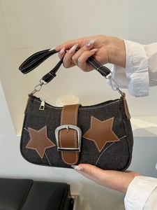 Detail of vintage denim shoulder bag with brown leather star patch and contrast stitching