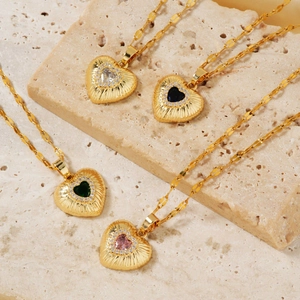 Golden heart pendant necklaces with vibrant zircon stones on a beige stone base