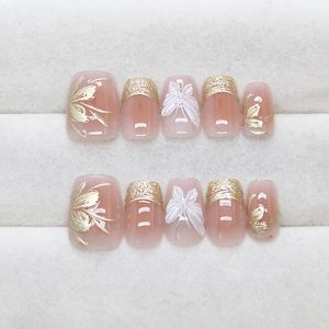 Unghie finte fatte a mano rosa nudo con linee floreali dorate e decorazioni a farfalla