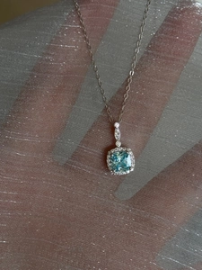 Close-up of square light blue gemstone pendant with crystal halo on silver chain