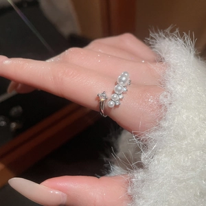 Close-up of elegant silver open ring with pearls and zircon on model with white sleeve