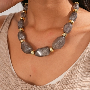 Close-up of grey irregular acrylic beads with glitter texture and gold metal rings