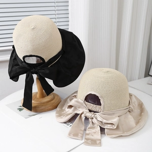 Wide brim sun hat with bow decoration in beige and black straw design for summer
