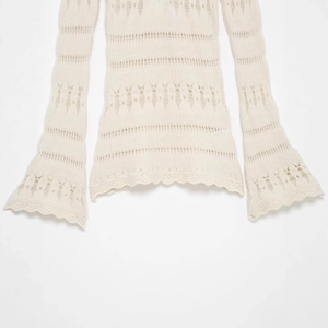 Off-white pointelle knit sweater featuring elegant flare sleeves and scalloped edges