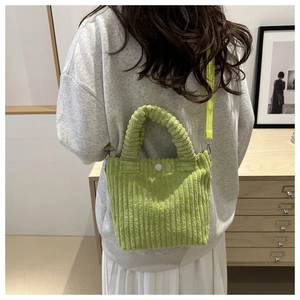 Close-up of light green corduroy bucket bag with velvet texture and magnetic snap