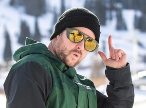Close-up of yellow lens polarized sports sunglasses and dark green ski jacket in snow