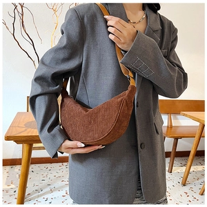 Close-up of brown corduroy dumpling bag worn over shoulder with grey blazer