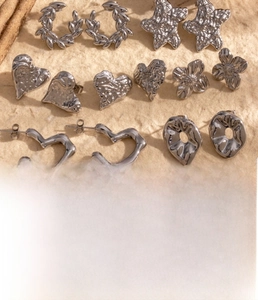 Macro shot of titanium steel heart and flower earrings with hammered metal texture
