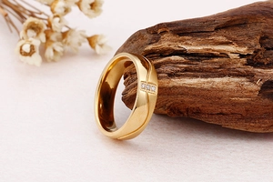 Gros plan d'une bague en acier inoxydable doré avec trois zircons sur bois naturel