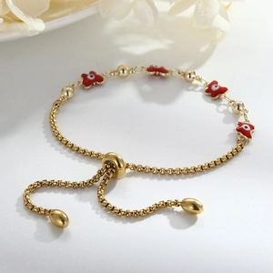 Detail of gold adjustable bracelet featuring a red butterfly enamel evil eye charm