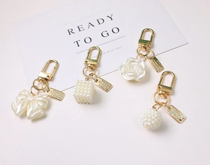 Detail of elegant pearl bow and rose charms with gold metal hardware for keychains