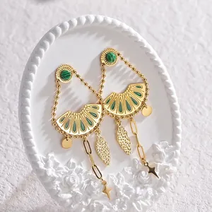 Macro detail of vintage gold earrings with green malachite inlay and leaf charms
