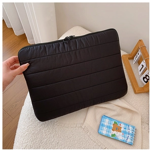 Detailed view of black quilted laptop sleeve with zipper closure and soft padded texture