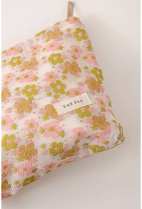 Detail of floral makeup bag with mesh overlay and H&R BAG logo on white background