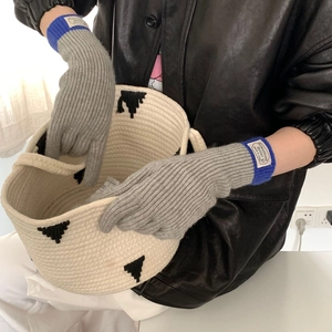 Detail view of thick gray knit gloves with blue cuffs and touch screen fingertips