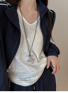 Detail of silver balloon dog pendant on black cord necklace worn on model for y2k street style