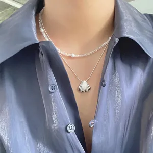 925 silver shell pendant necklace with pearl layered chain worn on blue silk shirt