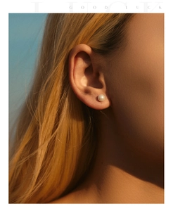 Classic white pearl earrings on model with high-gloss finish and natural lighting