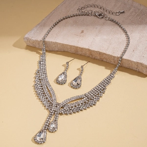 Detail of silver rhinestone necklace set with teardrop pendants on stone background