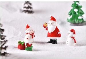 Close-up of resin Santa, snowmen, and gift boxes in a snowy Christmas landscape scene