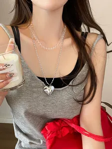 Detail of layered double heart necklace with transparent beads and silver pendant