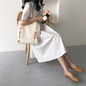 Minimalist beige canvas tote bag detail with red printed text for daily shopping
