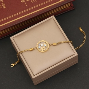 Detail of gold evil eye bracelet with clover charms on a vintage book display
