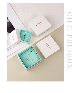 Close-up of white jewelry gift box set with turquoise lining and gold butterfly necklace