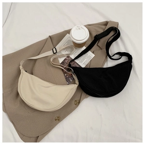 Flat lay of nylon crescent bags in beige and black with adjustable straps and zip closure