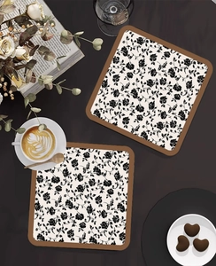 Detail view of two square floral heat-resistant coasters on a vintage wooden coffee table