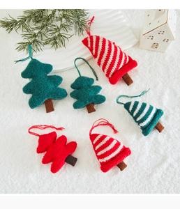 Close-up of knitted Christmas tree ornaments on white snow background with pine branch decor