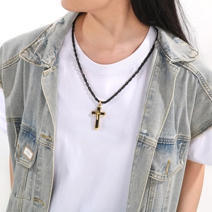 Close-up of a gold cross pendant with black inlay worn on a black bamboo chain necklace