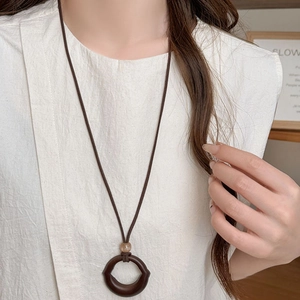 Detail of vintage acrylic resin round pendant on dark brown minimalist cord necklace