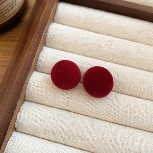 Gros plan de boucles d'oreilles rondes en velours rouge sur un écrin en bois vintage