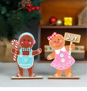 Detail of wooden gingerbread man and girl figurines with JOY text on festive background