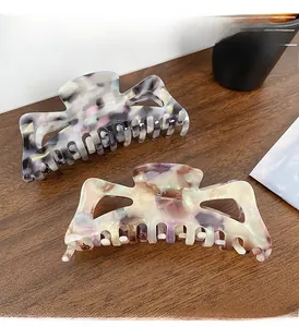 Detailed top view of two large hollow acetate hair claws in grey and beige marble patterns