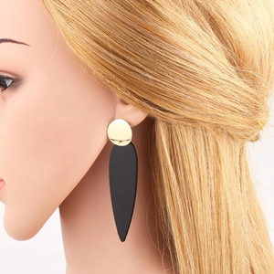 Elegant gold earrings with black teardrop pendant worn by a model in a profile view