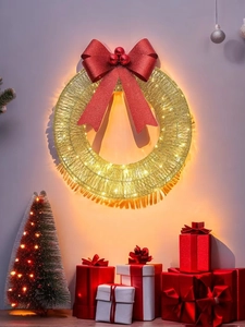 Detail of a lighted golden mesh Christmas wreath with red bow and warm LED lights