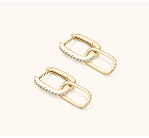 Macro detail of gold-plated double-loop earrings with shimmering pavé zircon stones