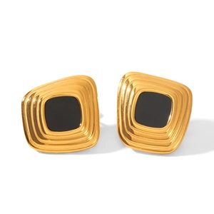 Macro detail of 18k gold geometric square earrings with black enamel inlay and tiered texture