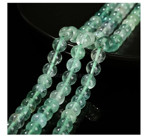 Macro shot of natural green fluorite round beads spilling from a black bowl