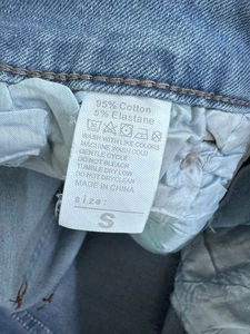 Primer plano de la etiqueta de cuidado con 95% algodón y talla en los shorts vaqueros