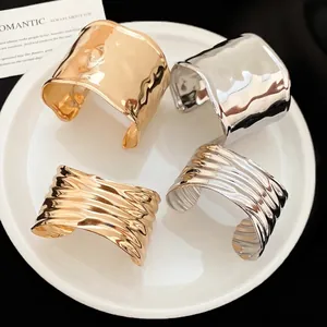 Set of four textured metal open bracelets in gold and silver with fluid wavy patterns