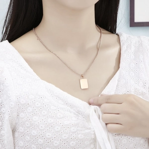 Detail of rose gold padlock pendant on bead chain worn by a model in lace top