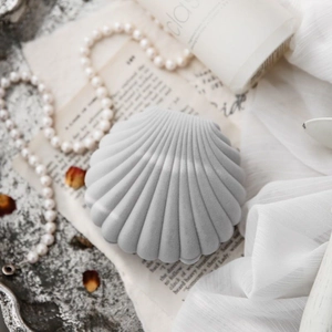Macro view of shell-shaped velvet jewelry box in light grey with vintage pearl background