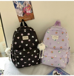 Detail of strawberry print backpacks in black and purple with fluffy white pendants